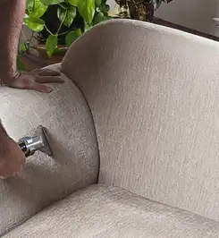 Professional upholstery cleaner deep-cleaning a fabric sofa with a handheld extraction tool and hose Spokane, WA.